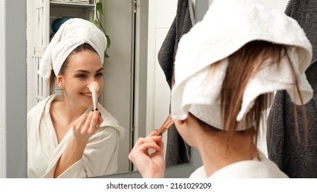 Makeup and cosmetic. Woman applying foundation makeup on her face with a makeup brush. Bathroom after showering concept. - Powered by Shutterstock
