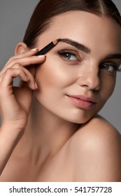 Makeup Cosmetics. Closeup Of Beautiful Sexy Girl Using Professional Cosmetic Pencil. Portrait Of Glamorous Female Model With Beauty Face Contouring Eyebrows With Brow Pencil. High Resolution