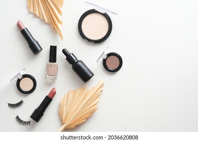 Make-up cosmetics with dried leaves on white background. Beauty products design, flat lay, top view.