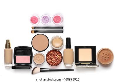 Make-up cosmetics set of liquid and cream foundations, compact and loose powder in various tones, bronzing pearls, blush, eye shadows and brushes isolated on white background. Top view point.