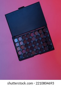 Makeup Eye Shadow Palette Floating In The Air, Isolated In Blue-red Neon Gradient Light. Levitating Objects. Minimal Concept