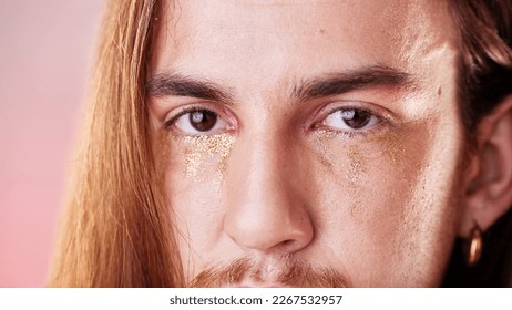 Makeup, eyes and portrait of gen z man with serious expression on face with pink background. Gold, glitter tears and art, zoom on eye cosmetics on non binary, transgender or gender neutral lgbt model - Powered by Shutterstock