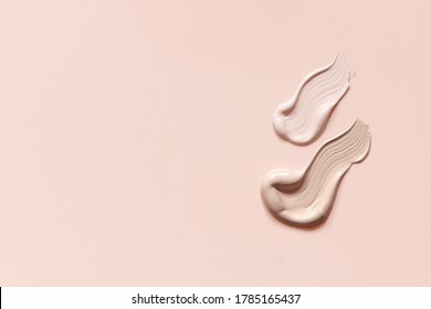 Makeup foundation cream strokes of different shades on skin tone color background. Nude pink creamy concealer smudges