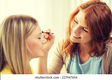 makeup, friendship and leisure concept - two smiling teenage girls applying make up at home - Shutterstock ID 227947654