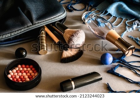 Makeup kit. On the table are blush, lipstick, eau de parfum, makeup brushes and a bag for cosmetics. Horizontal photo.