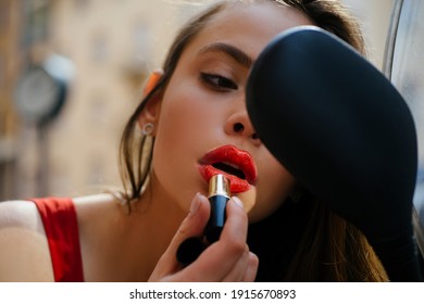 Makeup on walk. City life fashion. Sexy girl with red lips put lipstick looking in a mirror of motorcycle. Street vogue