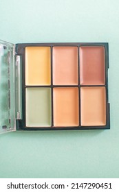 Make-up palette with colorful concealers on mint background. Selective focus.
