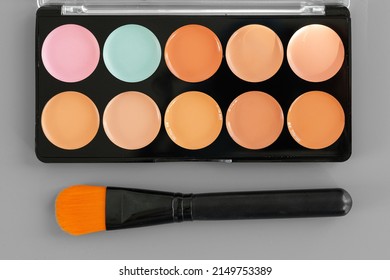 Make-up palette with colorful concealers on gray background