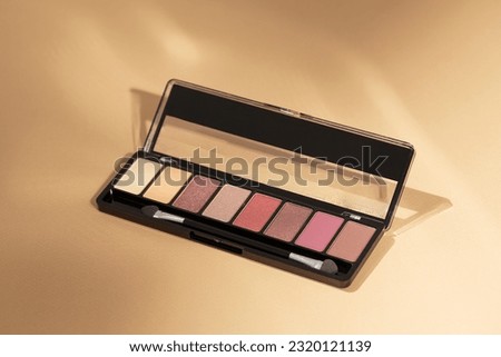 Make-up palette over a beige background. Professional multicolor eye shadow makeup palette. Cosmetic products. Classic nude shades. Minimal composition. 