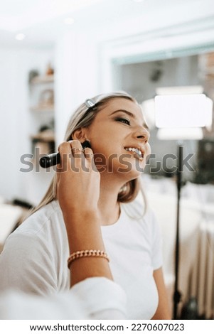 Makeup process. Professional make-up artist using brush on model face. Applying face foundation and tone to skin. Close up portrait of beautiful blonde woman in beauty salon. 