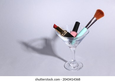 Makeup Products In A Cocktail Glass On A Gray Background