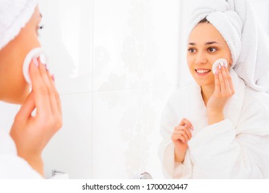 Makeup Removal Procedure. A Woman In A Bathrobe With A Towel On Her Head Washes Her Face In The Bathroom. Cleansing Face Tonic.