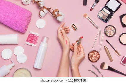 Make-up Remover Accessories. Flat Lay Background Womens Hands Try Cosmetics, Cotton Branch, Cotton Pads, Cosmetic Bottle Containers, Pink Towel, Various Make-up Cosmetics, Mascara, Powder, Lipstick.