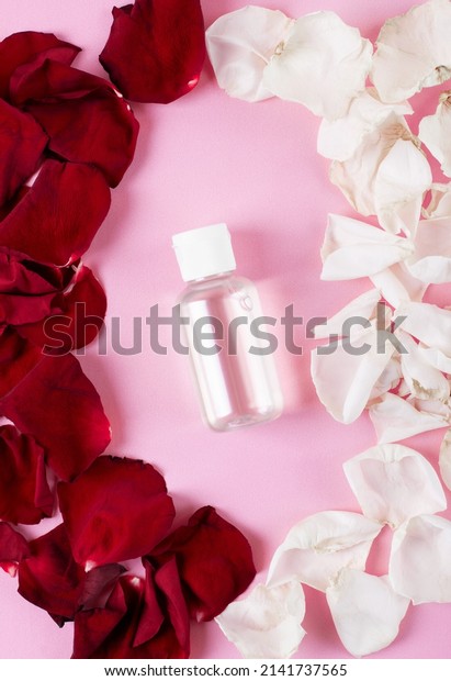 Make-up remover or beauty product with\
rosewater with red and white rose petals on pink background. Mockup\
packaging design. Creative\
presentation