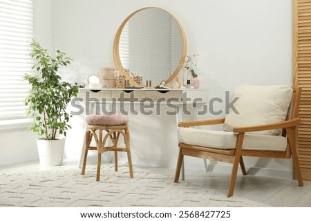Makeup room. Dressing table with mirror, different beauty products, stool, armchair and houseplant