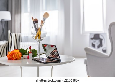 Makeup set lying on white round table next to armchair