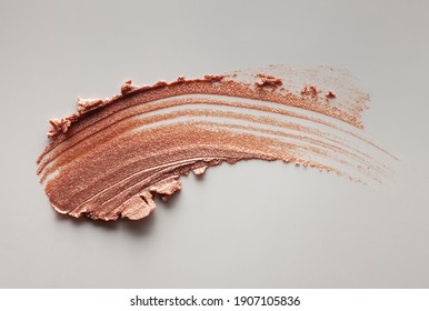 Make-up shimmer mousse foundation concealer bronzer and highlighter smudge creamy powder on gray background