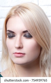 The makeup style smoky eyes at the closed eyes of a girl blondes on a light background