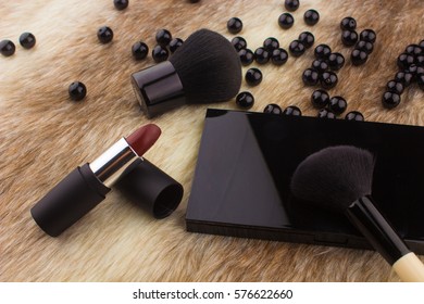 Makeup tools on Fur background / featuring eyeshadow palette, lipstick, makeup brushes on a fury background