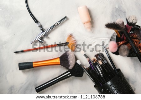 Makeup tools for professional makeup artist. Makeup brushes. Airbrush and jar of paint. Makeup tools and accessory on concrete gray background. Fashion and beauty concept.