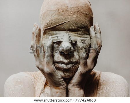 in makeup, a woman in bandages and clay is like a mummy without eyes on a monophonic background. Halloween theme