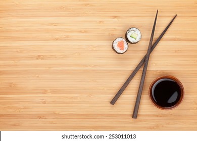 Maki sushi, chopsticks and soy sauce on bamboo wooden table background with copy space