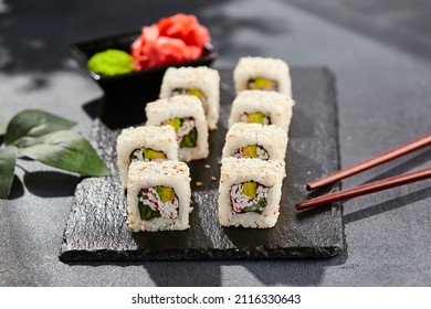 Maki Sushi On Dark Stone Table. Sushi Roll California In Sesame. Maki Sushi With Crab, Avocado, Cucumber Inside, Sesame Outside. Style Concept Japanese Menu With Black Background