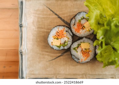 Maki sushi rolls with vegetables and seafood on a beige cloth with green leafy garnish. - Powered by Shutterstock