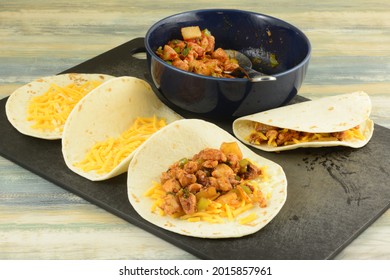 Making BBQ Chicken Pineapple Quesadillas By Filling Tortillas With Shredded Cheese And Cooked Filling On Cutting Board