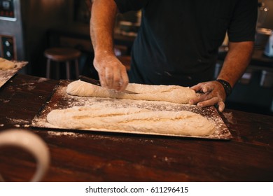 Making the bread, the cook cut it with a knife - Shutterstock ID 611296415