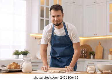 Making bread. Man rolling dough at wooden table in kitchen - Powered by Shutterstock