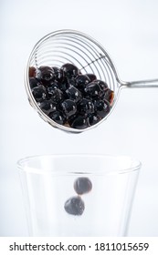 Making Bubble Tea, Scoop And Pour Cooked Brown Sugar Flavor Tapioca Pearl Bubble Balls Into Cup On White Wooden Table Background, Close Up, Copy Space.