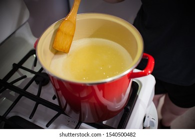 Making Caramel Candy Stirring With Wooden Spoon In Red Pot On White Stove Caucasian Hand 