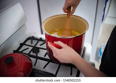 Making Caramel Candy Stirring With Wooden Spoon In Red Pot On White Stove Caucasian Hand 