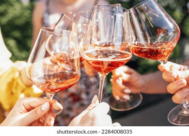 Making a celebratory toast with sparkling wine. Female hands holding glasses of rose champagne. Birthday, holiday, party and friendship concept.