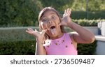 Making child in pink top pulling cheeks and sticking tongue in sunlit backyard, with emoji icons. Kid, garden, playful, cheerful, sunny, outdoors, candid