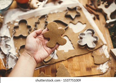 Making christmas gingerbread cookies. Hand holding raw gingerbread man cookie on background of dough, metal cutters and anise, ginger, cinnamon, pine cones, fir branches on rustic table. - Powered by Shutterstock