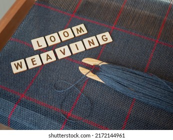 Making cloth in the traditional way. Woven blue fabric with red stripes. Concept of loom weaving, cloth art and craft. Weaving loom, wooden shuttle and handwoven scarf, selective focus