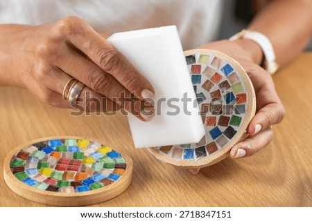 Making coasters at home, applying a final protective coat to coaster's surface during craft work. Highlights precision, coating control, and structured artistic finishing.
