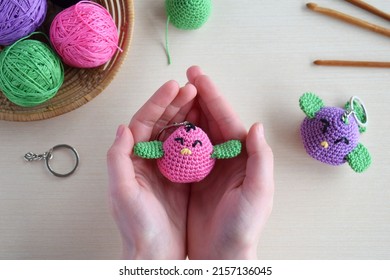 Making colored crochet bird. Toy for babies or trinket.  On the table threads, needles, hook, cotton yarn. Handmade gift. DIY crafts concept.