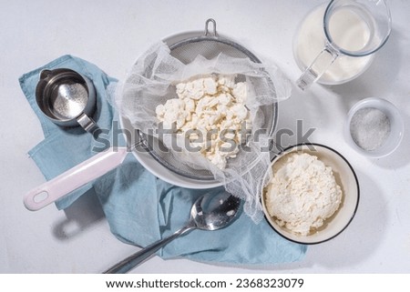 Making cottage cheese, homemade fermenting dairy product. Homemade cottage cheese in cheesecloth bags on kitchen table, woman hands drain cheese at home top view copy space