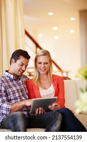 Making Decisions As A Team. A Happy Couple Sitting On Their Couch Working On A Digital Tablet - Copyspace.