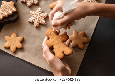 Making decoration of gingerbread man cookie from piping bag with sugar glaze. - Shutterstock ID 2396424993