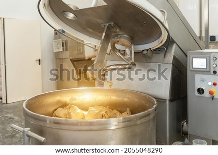 Making dough for bread in a kneader in a bakery. Industrial mixer for kneading dough. One of the stages of making bread dough