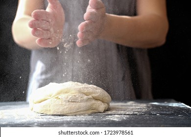 Making dough by hands at bakery or at home. Flour cloud in the air. Close up of woman chef hands preparing for kneading the dough on the table, powdering with flour. dough for bread, pasta or pizza - Powered by Shutterstock