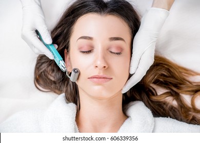 Making dry needlying procedure on woman's face in the cosmetology office