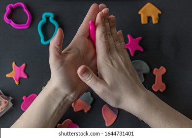 Making edible marzipan figures with your hands and cookie cutters to decorate baking. Girl's hands in the photo are in the process of preparation. Ready and packed gingerbread cookies on the table.
