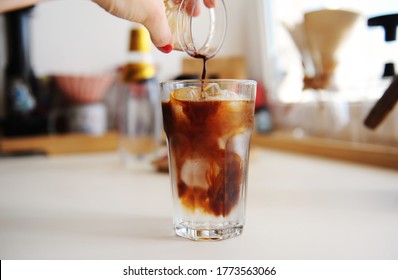 Making espresso tonic. Pouring espresso into glass with tonic and ice. Summer recipe
