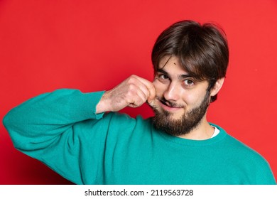 Making Faces. Portrait Of Young Bearded Man Pulling His Cheek With Funny Face Isolated Over Rd Studio Background. Concept Of Youth, Emotion, Facial Expression, Fashion, Lifestyle, Ad