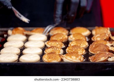 Making fresh poffertjes in stove pan on market, Traditional Dutch batter treat, Resembling small fluffy pancakes they are made with yeast and buckwheat flour, Poffertjes are popular in the Netherlands